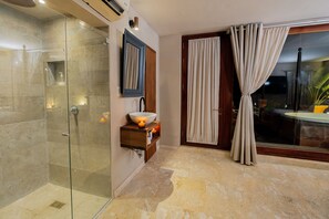 Une salle de bain moderne dotée d’une douche à parois de verre, d’un meuble-lavabo en bois avec un vasque et d’une grande porte-fenêtre coulissante donnant sur un balcon.