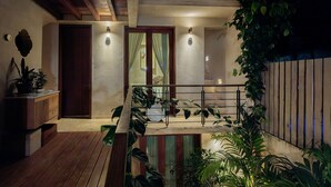 Eine Holzterrasse mit Geländer, umgeben von Kübelpflanzen und einer Treppe, die zu einer erhöhten Ebene führt.