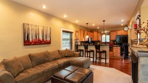 A modern living room with a sectional sofa, a coffee table, and a fireplace. - Wolf's Den (Ellicottville)