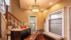 A kitchen with a wooden island, stools, and a hanging light fixture. - Wolf's Den (Ellicottville)