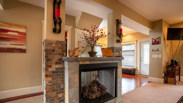 A living room with a fireplace, a stone accent wall, and a door leading to another room. - Wolf's Den (Ellicottville)