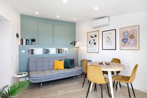 Een moderne woonkamer met een bank, eettafel, stoelen en wanddecoratie.