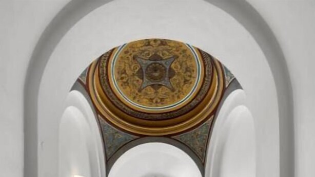 Ein Korridor mit gewölbter Decke und einer kuppelartigen, gemusterten Decke.