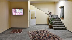 Un corridoio con una scala, una TV a parete e due tappeti sul pavimento.