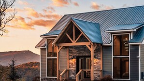 A modern house with a stone facade, a sloped metal roof, and a front porch. - Spacious 4BR|Indoor Pool|Hot Tub|Games|Fire Pit (Sevierville)