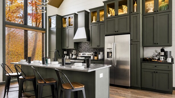 A modern kitchen with a central island, bar stools, a refrigerator, and a window with a view of autumn trees. - Spacious 4BR|Indoor Pool|Hot Tub|Games|Fire Pit (Sevierville)