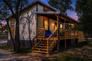 Eine Hütte mit Veranda, Holzstufen und einer überdachten Sitzgelegenheit.