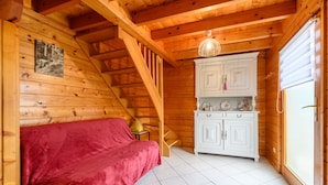 A wooden cabin interior with a bed, a staircase, a white cabinet, and a door. - “Our Chalet” with Mountain View, Private Terrace and Wi-Fi (vecoux)