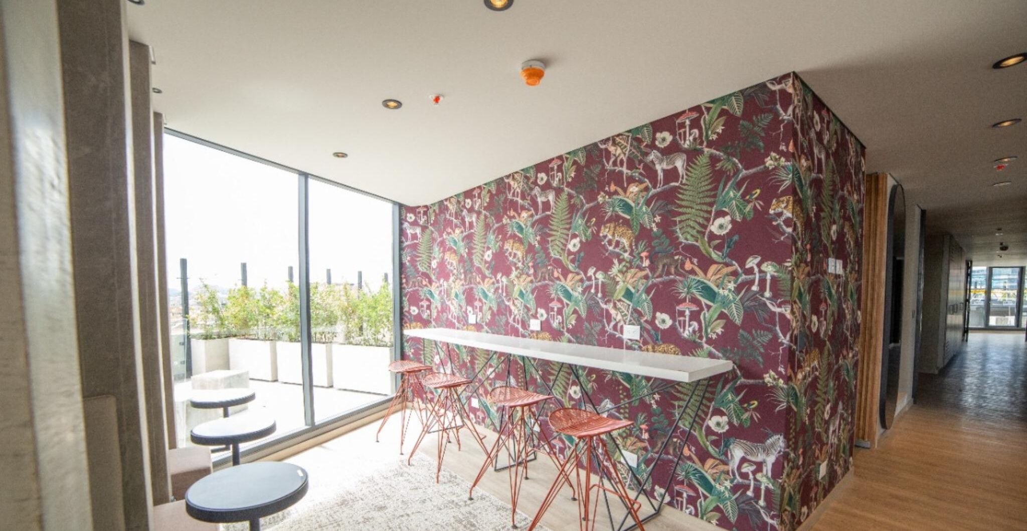 A modern interior with a patterned wall, a glass partition, and a bar area with stools.