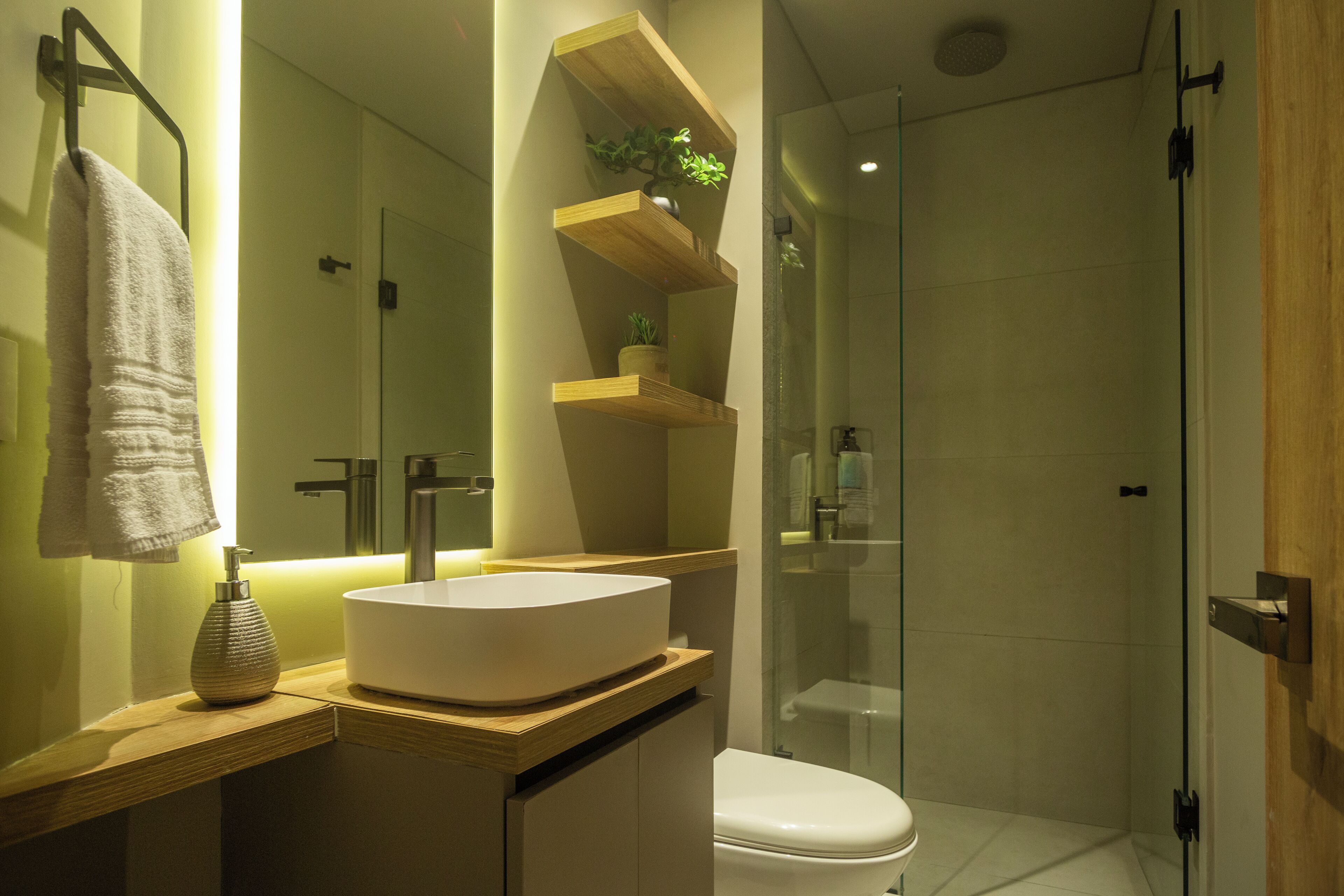 A modern bathroom with a large white sink, a toilet, and a glass-enclosed shower.