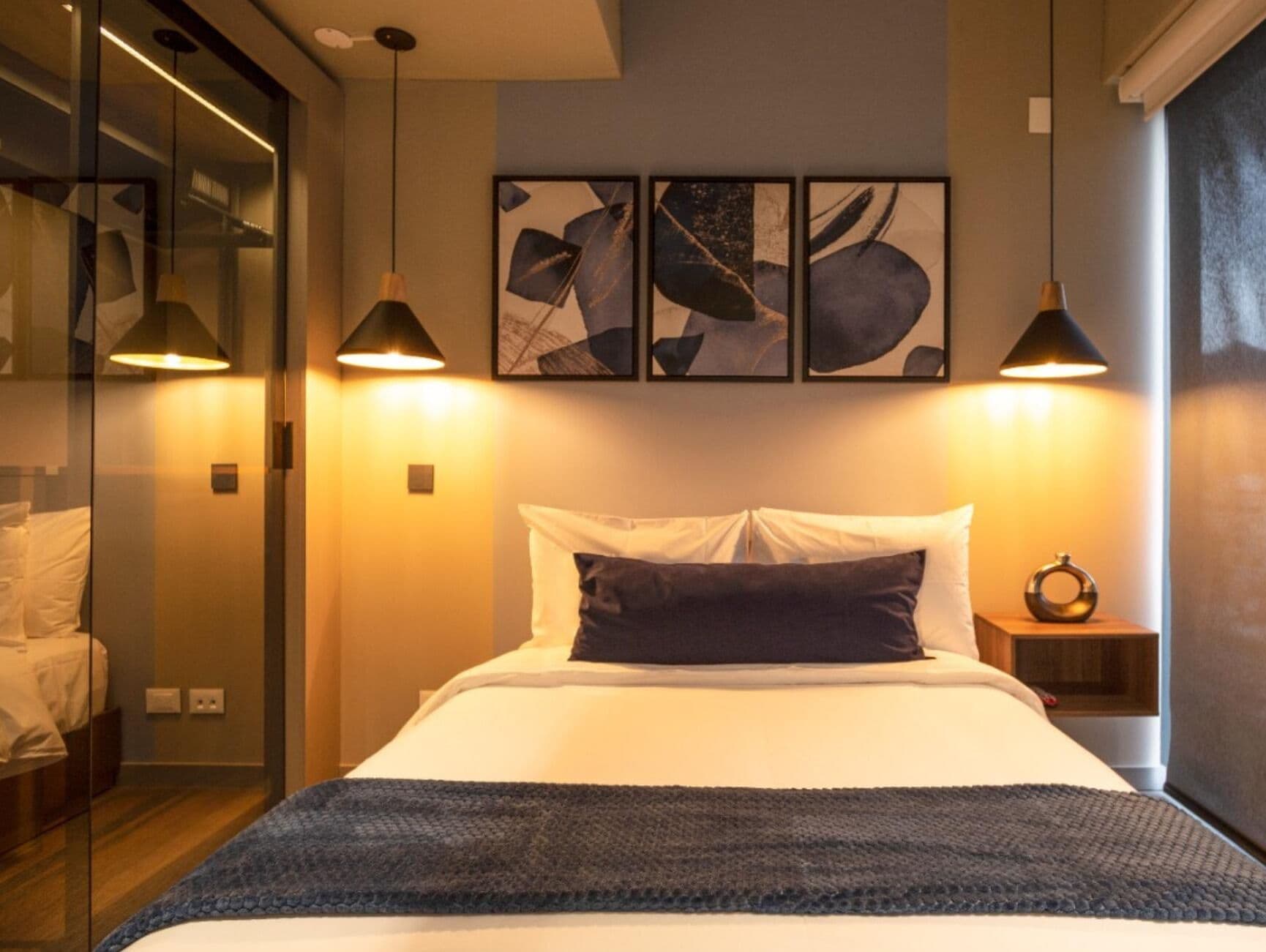 Une chambre à coucher moderne avec un lit, des tables de chevet et des œuvres d’art abstraites accrochées au mur.