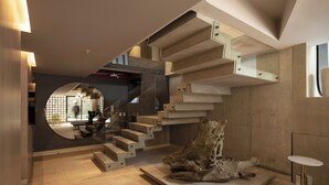Un interior moderno con un diseño de escalera único, un espejo grande y un trozo de madera a la deriva.