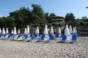 Am Strand, weißer Sandstrand, Liegestühle, Sonnenschirme