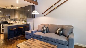 A modern kitchen with a bar area, a sofa, and a coffee table.