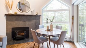 A dining area with a fireplace, round table, and chairs.
