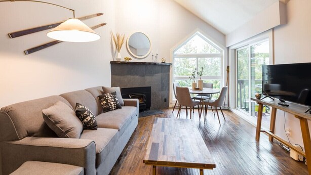 A modern living room with a sofa, fireplace, dining table, and TV.
