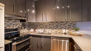 A modern kitchen with stainless steel appliances, a tiled backsplash, and a built-in dishwasher.
