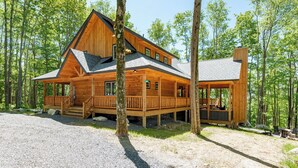 A wooden cabin with a porch, large windows, and a deck. - Cozy Log Chalet Near Wisp w/ Hot Tub (McHenry)