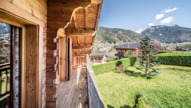 Une cabane en bois dotée d’un balcon donnant sur un paysage montagneux.