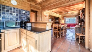L’intérieur d’un chalet en bois comprend un coin cuisine équipé d’un four à micro-ondes, d’une machine à café et d’un plan de travail recouvert de carreaux.