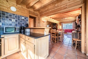 L’intérieur d’un chalet en bois comprend un coin cuisine équipé d’un four à micro-ondes, d’une machine à café et d’un plan de travail recouvert de carreaux.