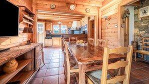 Un intérieur en bois comprenant une table à manger, des chaises, un téléviseur et un coin cuisine.