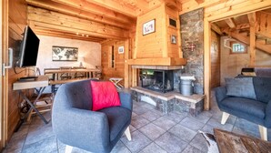 Un intérieur en bois avec une cheminée, des canapés et un coin repas.