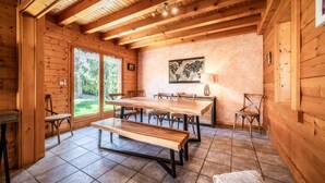 Un intérieur en bois comprenant une table à manger, des bancs, des chaises et une grande fenêtre.