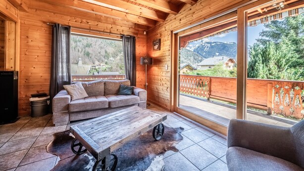 Une cabane en bois avec un canapé, une table basse et une vue sur un paysage montagneux.