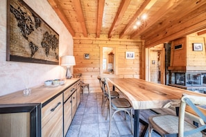 Un interno in legno con un lungo tavolo da pranzo, sedie, angolo cottura e una grande mappa appesa al muro.