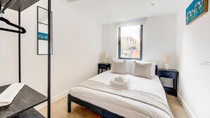Een slaapkamer met een bed, twee nachtkastjes, een raam en een hanglamp.