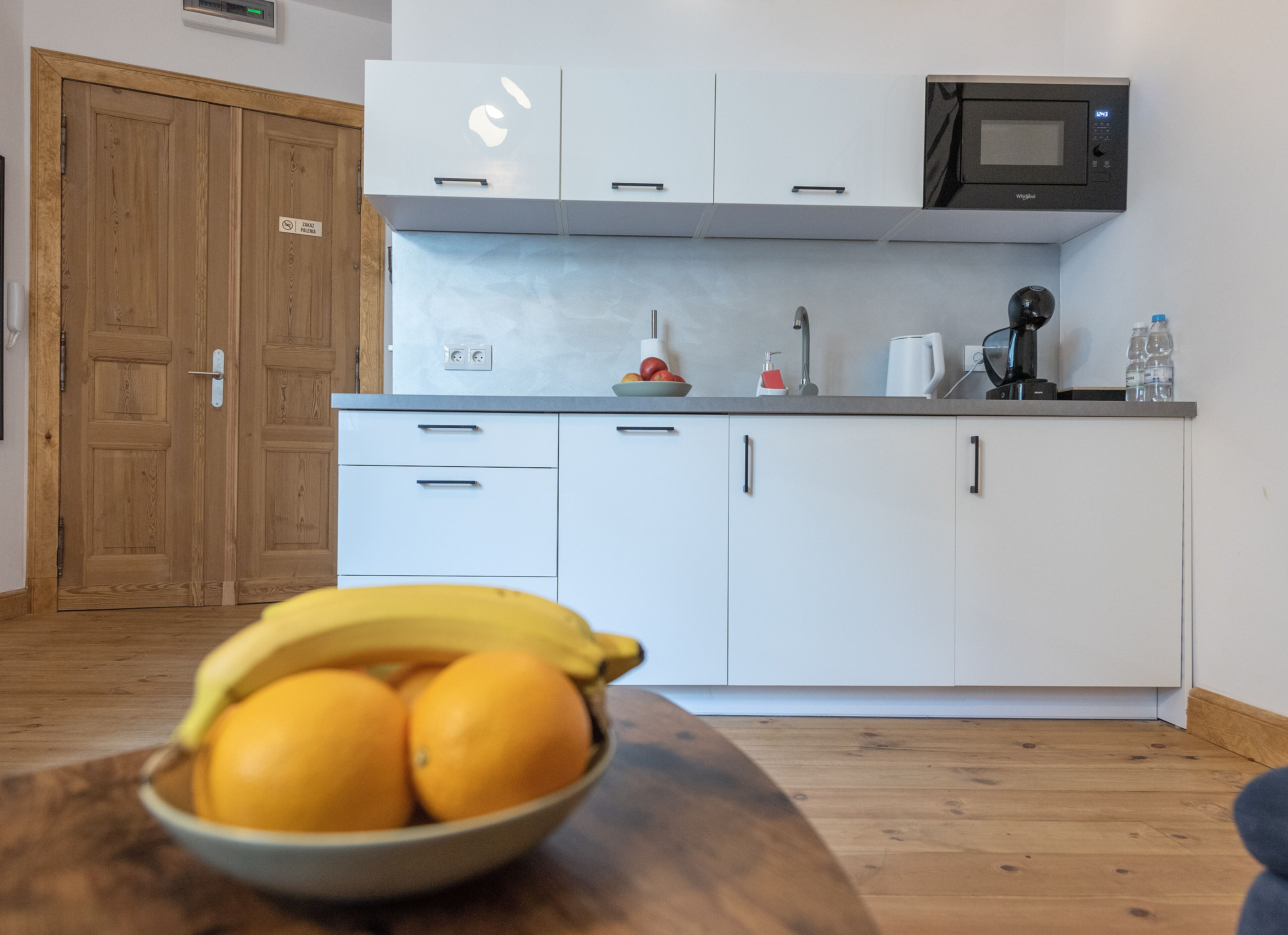 Una cocina moderna con armarios blancos, un microondas y un cuenco de fruta en la encimera.