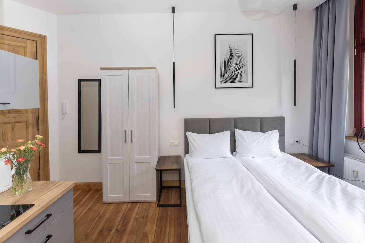 Une chambre à coucher comprenant un lit, une armoire, une table de chevet, un miroir et une œuvre d’art encadrée accrochée au mur.