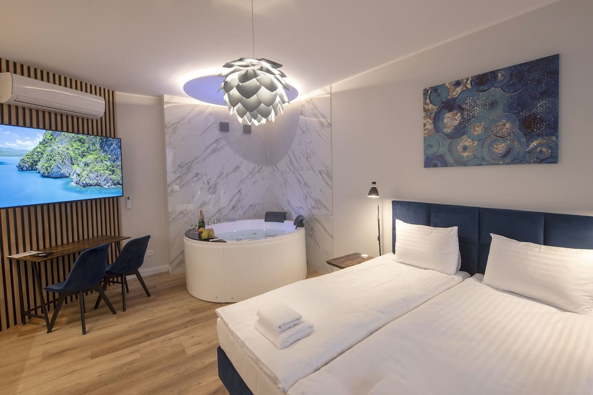 Une chambre d’hôtel moderne dotée d’un grand lit, d’un coin salon avec un téléviseur, d’une baignoire et d’un luminaire au plafond.