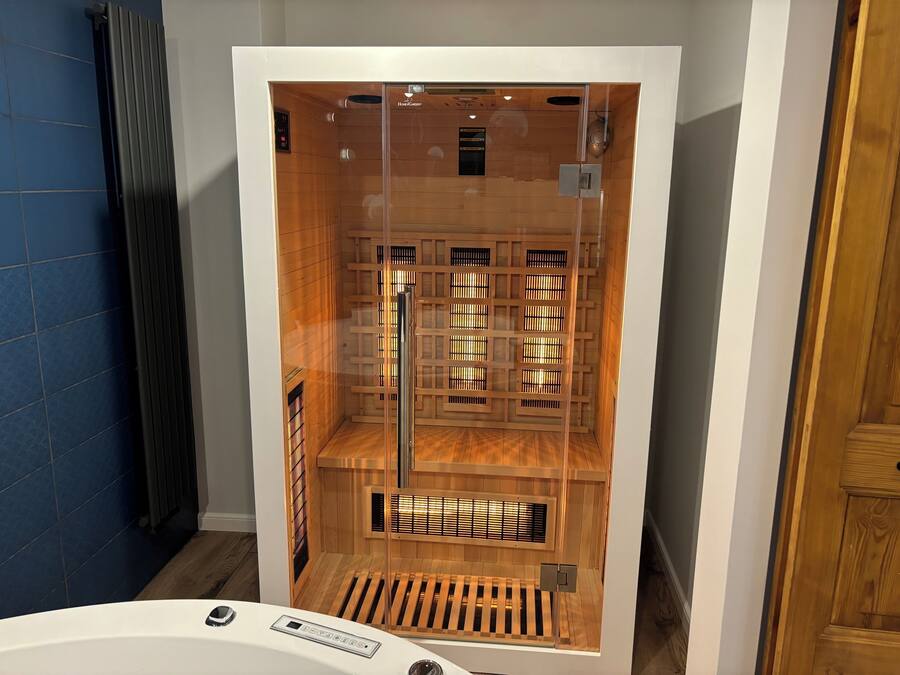 Uma sauna com interior de madeira, painel de controle e porta de vidro.