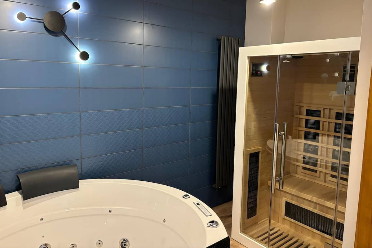 Ein modernes Badezimmer mit einer großen Badewanne, einer Duschkabine aus Glas und einer blauen Fliesenwand.