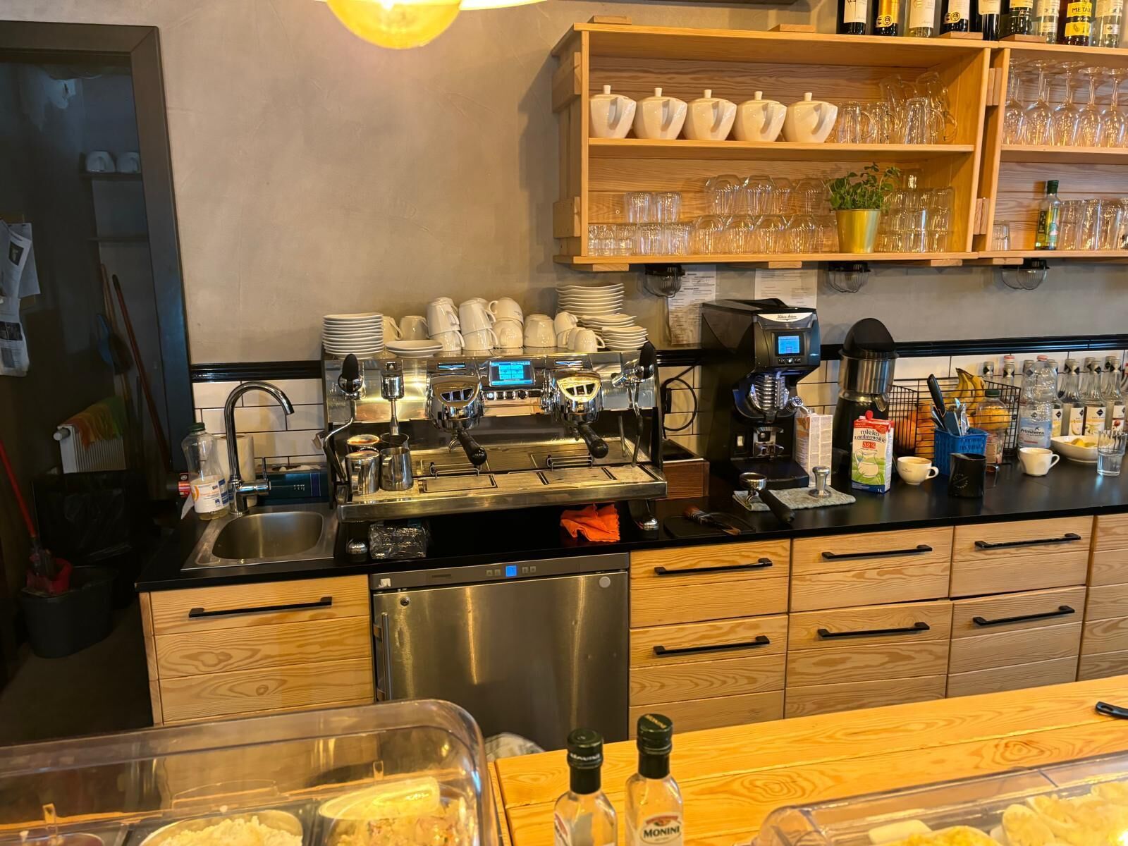 Ein Café mit Espressomaschinen, einem Spülbecken und verschiedenen Zubehörteilen für die Kaffeezubereitung.