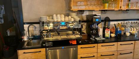 Ein Café mit Espressomaschinen, einem Spülbecken und verschiedenen Zubehörteilen für die Kaffeezubereitung.