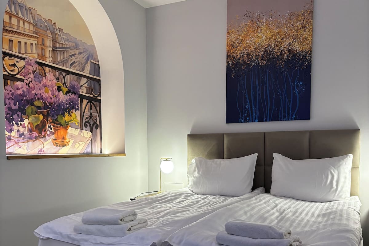 Ein modernes Schlafzimmer mit einem großen Bett, einem Blumenbild und einer Stadtansicht.