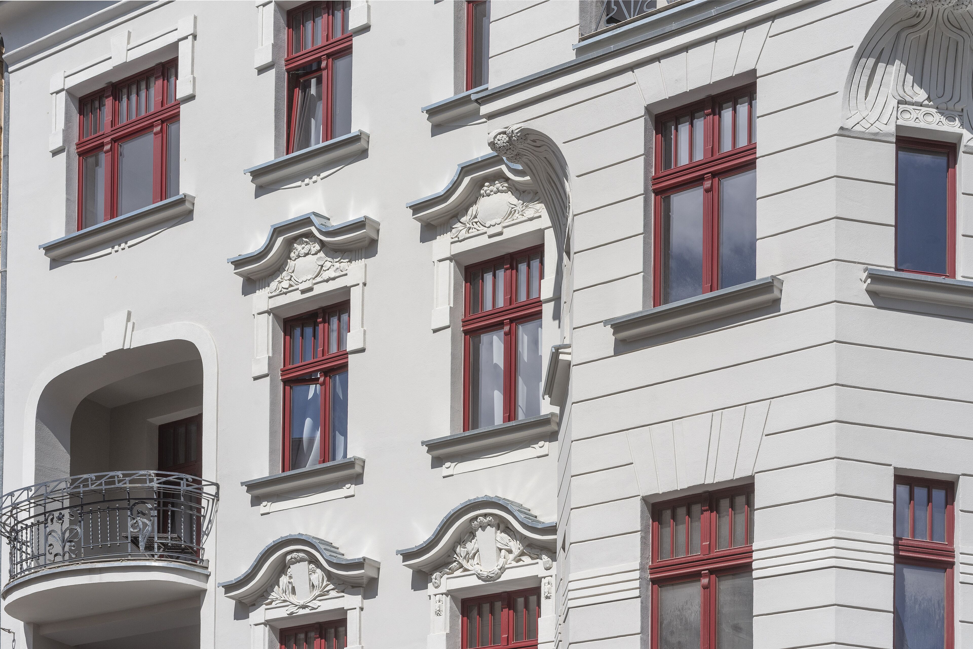Een gebouw met meerdere ramen, waarvan sommige rode raamkozijnen hebben, en decoratieve architectuurelementen.