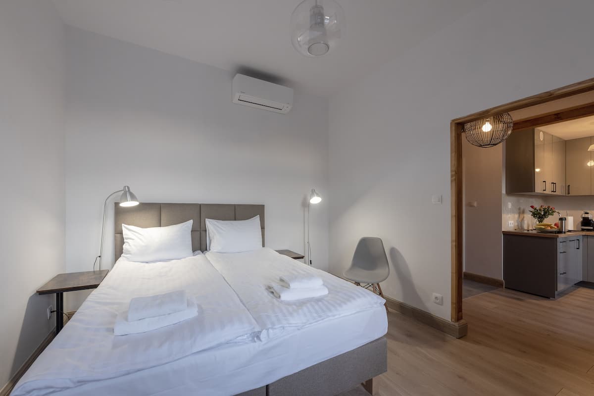 Une chambre d’hôtel moderne, dotée d’un grand lit, de lampes de chevet, d’un petit bureau et offrant une vue sur la cuisine.