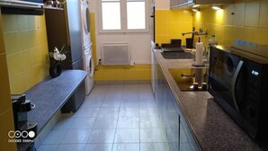 A compact kitchen with a washing machine, a sink, and a window. - Aramis Colibri 72m2, lit King-size, Baignoire duo (Paris)