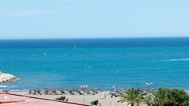 A beach with clear blue water, a few boats, and a palm tree. - Appartement 90m2, Lumineux, Climatisé, Tout Confort, vue Mer, Toutes Commodités (Benalmádena)