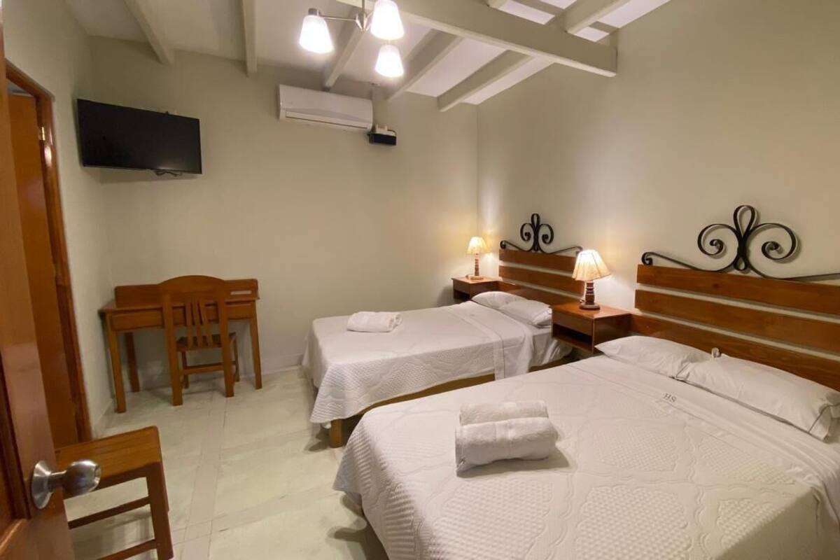 A hotel room with two beds, a TV, a desk, and a chair.