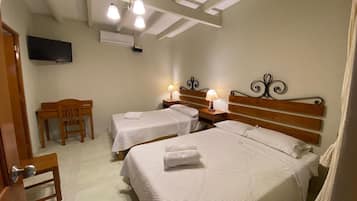 Quarto de hotel com duas camas, televisão, escrivaninha e uma cadeira.