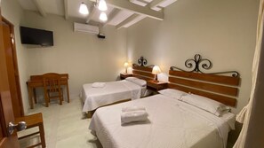 Una habitación de hotel con dos camas, televisión, escritorio y una silla.