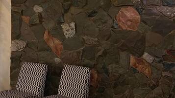Una habitación con pared de piedra y dos sillas estampadas.