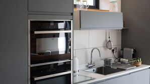 A modern kitchen with built-in ovens, a stainless steel sink, and a window above the countertop.