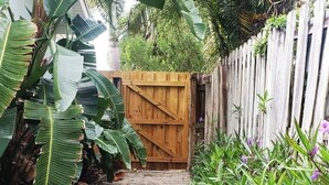 Un cancello di legno che conduce a un giardino rigoglioso, con piante lussureggianti e una recinzione in legno.