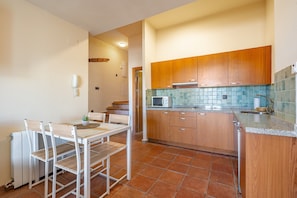 A kitchen with wooden cabinets, a microwave, and a dining table with chairs.